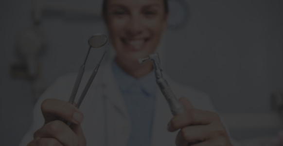 Smiling dentist holding dental tools during a pediatric dental visit.