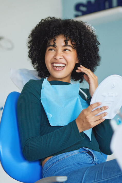 Happy patient reviewing her smile in a modern dental clinic