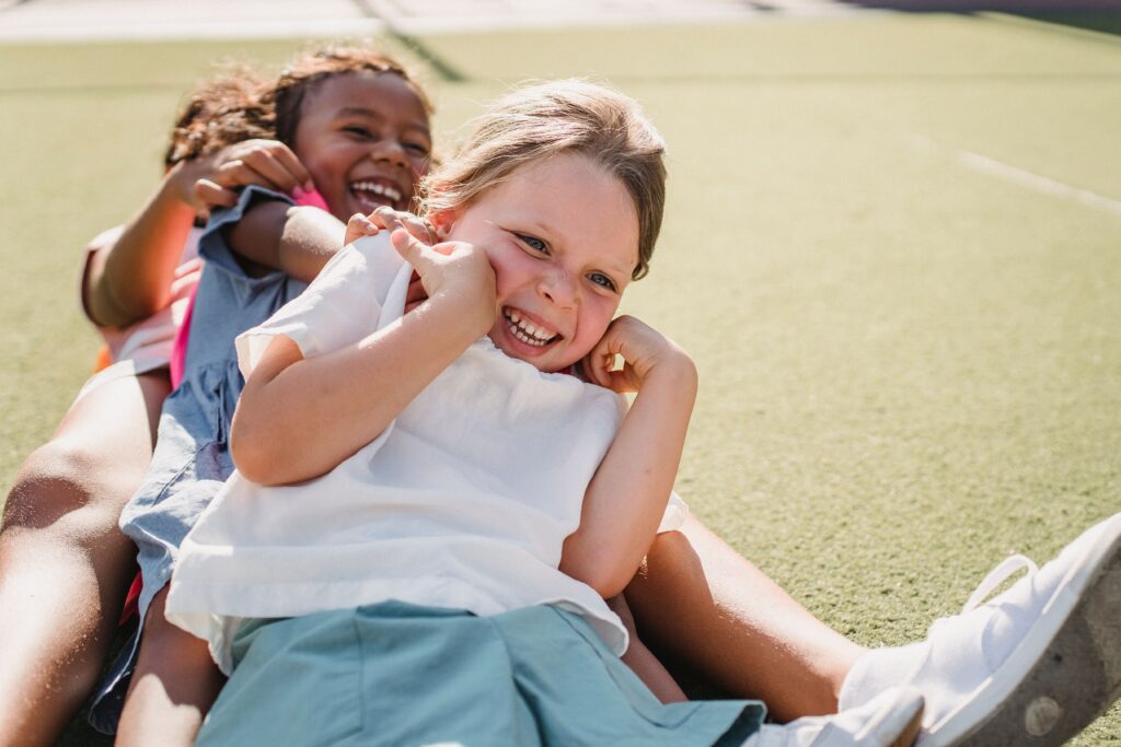 Children smiling and playing outside on a sunny day.